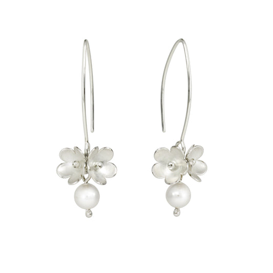 A pair of silver drop earrings featuring a small blossom flower cluster with a dangling round pearl, shown against a plain white background.