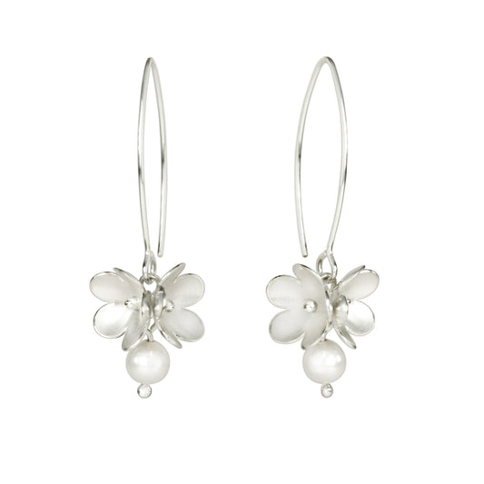 A pair of silver drop earrings featuring a small blossom flower charm with a dangling pearl bead, suspended from thin silver hooks against a plain white background.